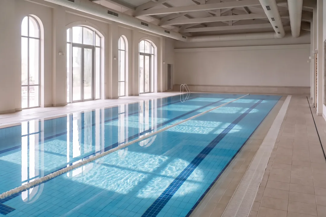 The same indoor pool after the filter work, its water crystal clear and blue, the floor lines sharp.